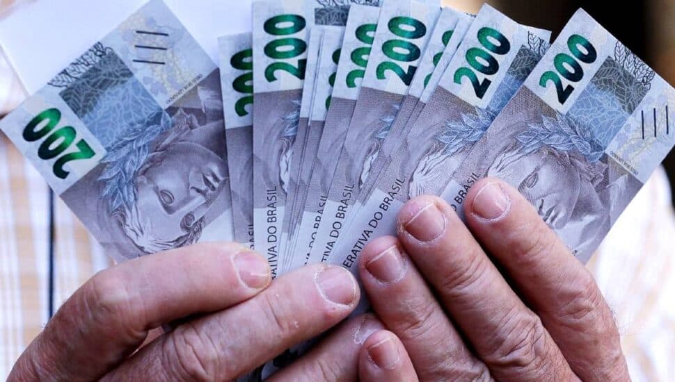 mão segurando nota de 200 reais
