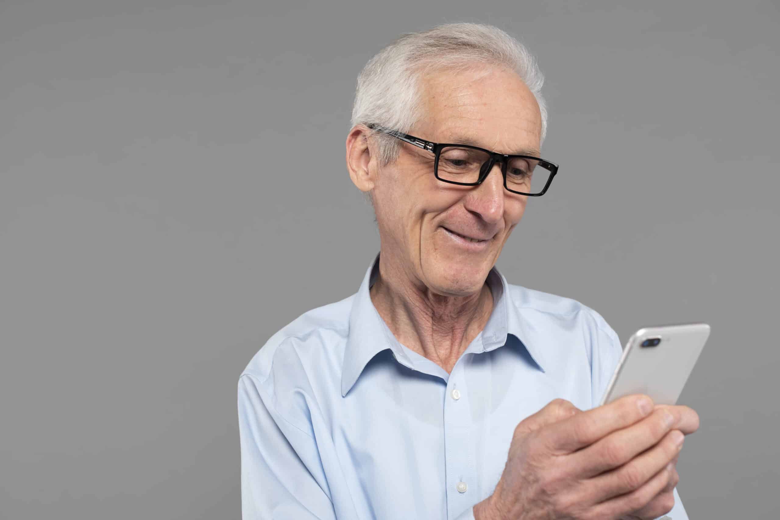 Aposentado lendo notícia no celular sobre saque extra do INSS