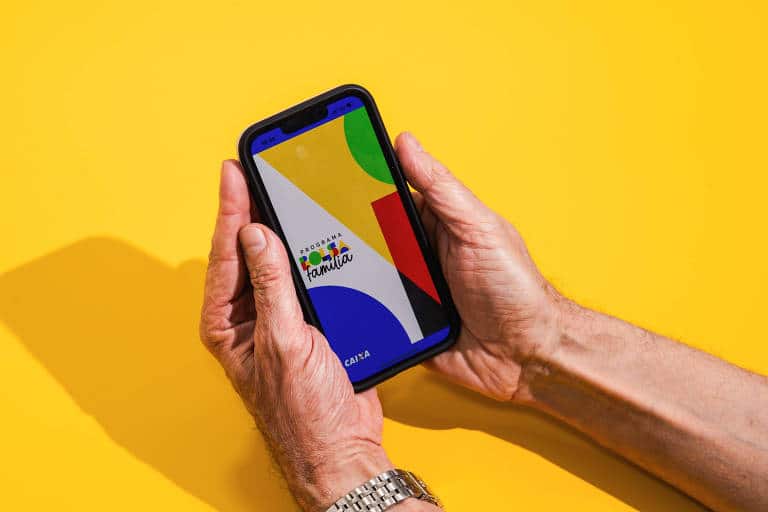 idoso segurando um celular com o aplicativo bolsa família