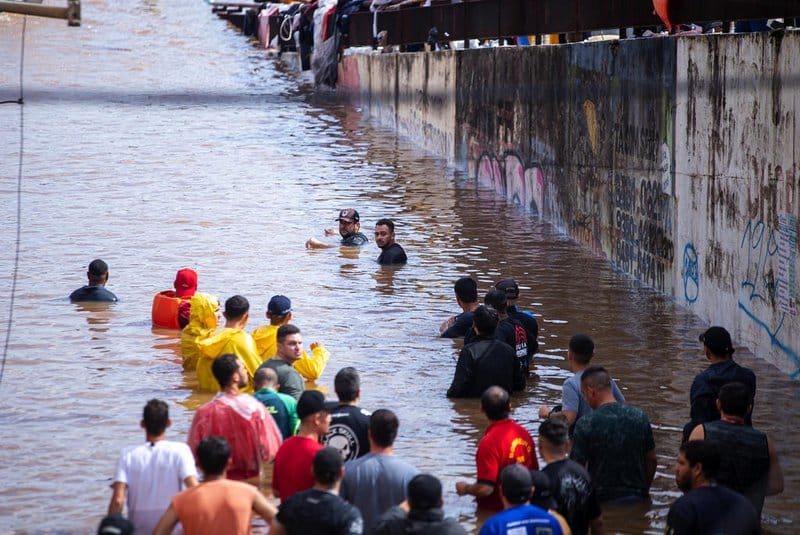 imagem de pessoas dentro da água da enchente no rio grande do sul