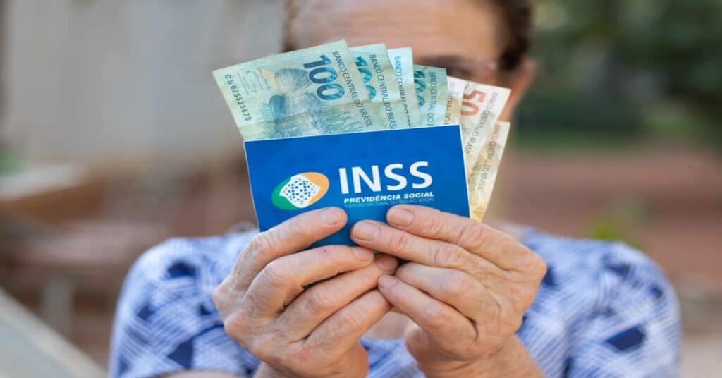 aposentada do inss segurando dinheiro e cartão do benefício