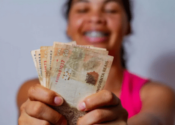 mulher jovem segurando várias notas de 50 reais