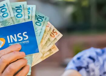 aposentada do INSS segurando dinheiro e o cartão do instituto