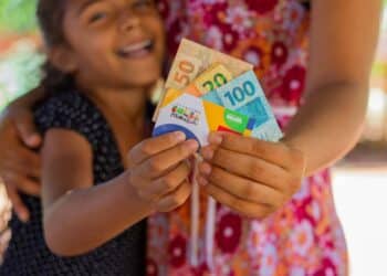 mãe e filha segurando dinheiro e cartão do bolsa família