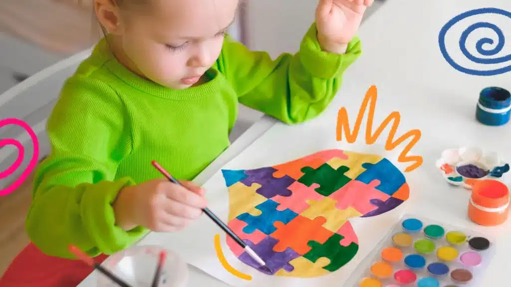 criança com autismo pintando um lindo coração colorido e em forma de quebra-cabeça, que representa o transtorno