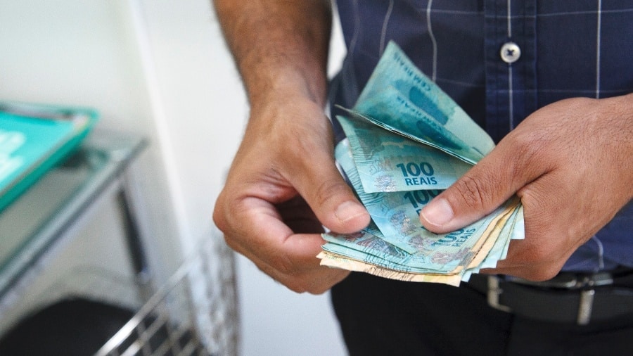 maos segurando notas de reais