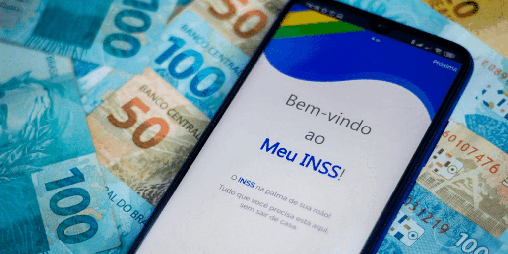 Celular em cima de diversas notas de dinheiro, aberto no app Meu INSS com 