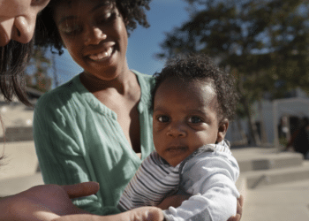 mãe com criança no colo em comunidade do Brasil
