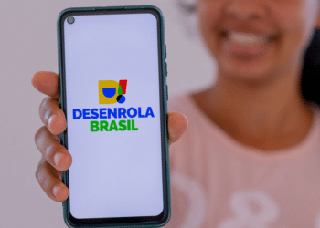 Mulher mostra tela de celular com logo do Desenrola Brasil