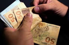 mãos segurando notas de dinheiro que caem com o pagamento da segunda parcela 13 salário INSS