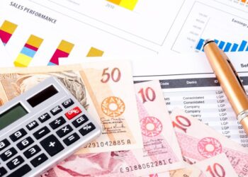 calculadora ao lado de caneta e dinheiro fazendo as contas das dívidas
