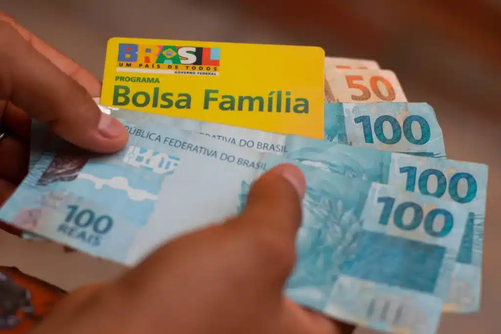 notas de cem e cinquenta reais e um cartão do bolsa família