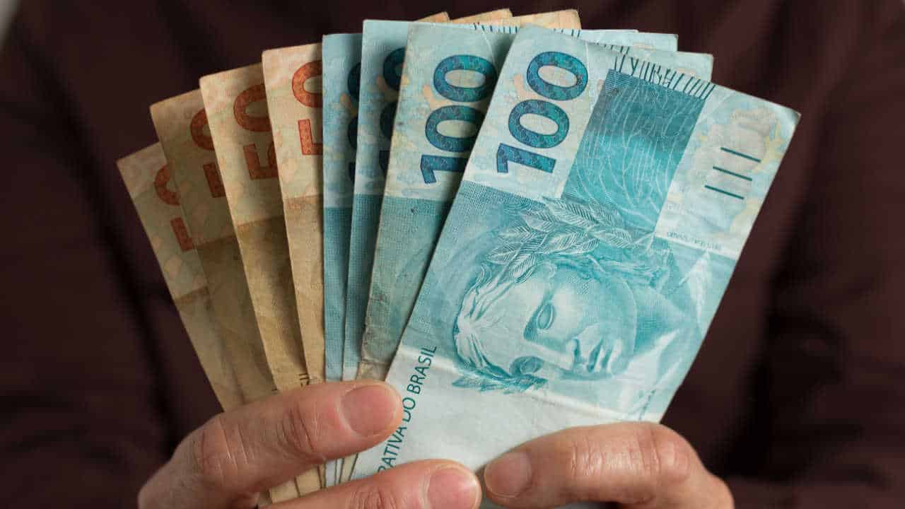 dinheiro na mão mostrando antecipação do bolsa familia
