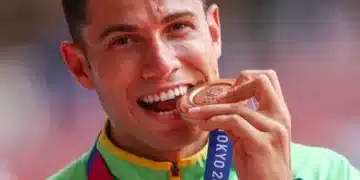 Atleta Thiago Braz mordendo medalha de bronze