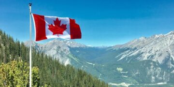 Bandeira do Canadá de frente a uma paisagem do país (Fonte: Reprodução/Getty Images)
