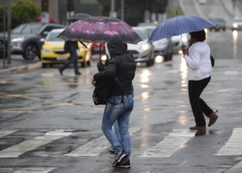 Pessoas com roupa de frio e sombrinhas na rua (Fonte: Reprodução/Estadão)