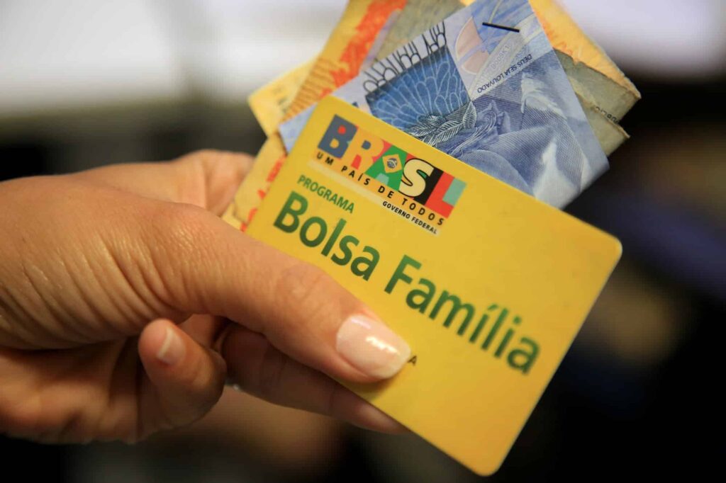 imagem de uma pessoa com o cartão e o dinheiro do Programa Bolsa Família