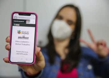 imagem de uma moça segurando o celular e mostrando o app do Programa Bolsa Trabalho