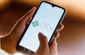 imagem com uma pessoa com o celular nas mãos e a tela do Pix