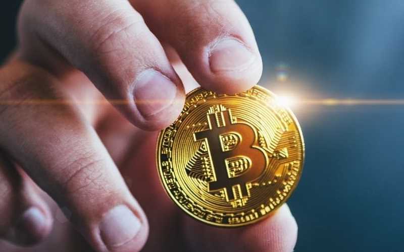 imagem de uma mão segurando uma criptomoedas