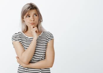 mulher loira, pensativa com mão no queixo, olhando para o lado