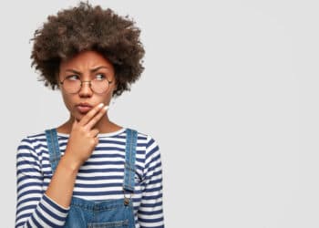 mulher negra, pensativa, segurando o queixo, olhando para o lado