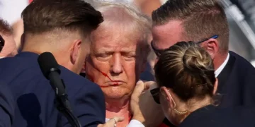 Donald Trump sangrando em atentado em comício. (Fonte: InfoMoney).