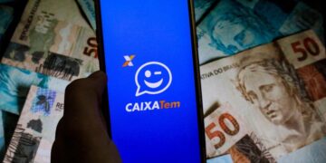 celular aberto no caixa tem ao lado de muito dinheiro