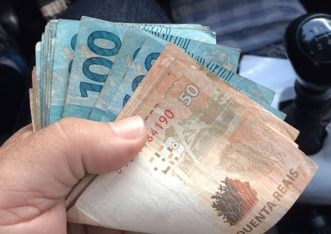 pessoa segurando cédulas de dinheiro