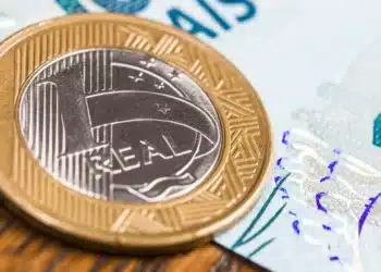 cédula de 100 reais ao lado de moeda de 1 real