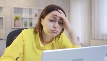 Mulher preocupada na frente do computador. (Fonte: Vecteezy).