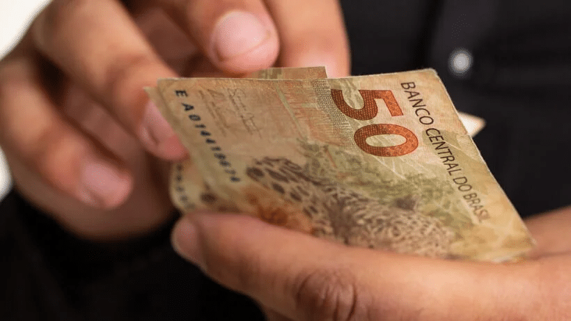 pessoa segurando cédulas de dinheiro
