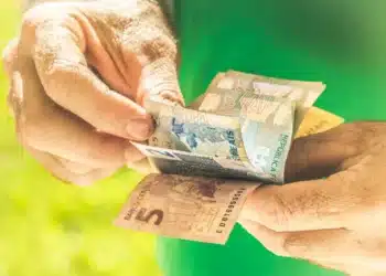 Aposentado segurando bônus de 200 reais do programa Voa Brasil. (Fonte: shutterstock).