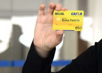 mão segurando o cartão amarelo do bolsa família