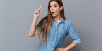 mulher jovem usando camisa azul apontando para cima com a boca aberta