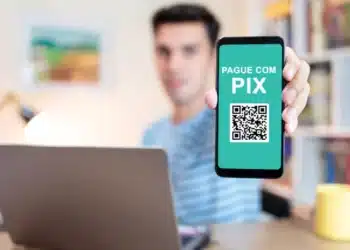 Homem segurando celular na tela do pix. (Fonte: shutterstock).