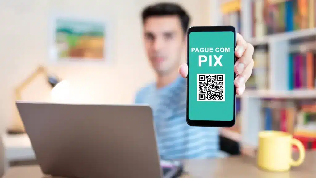 Homem segurando celular na tela do pix. (Fonte: shutterstock).