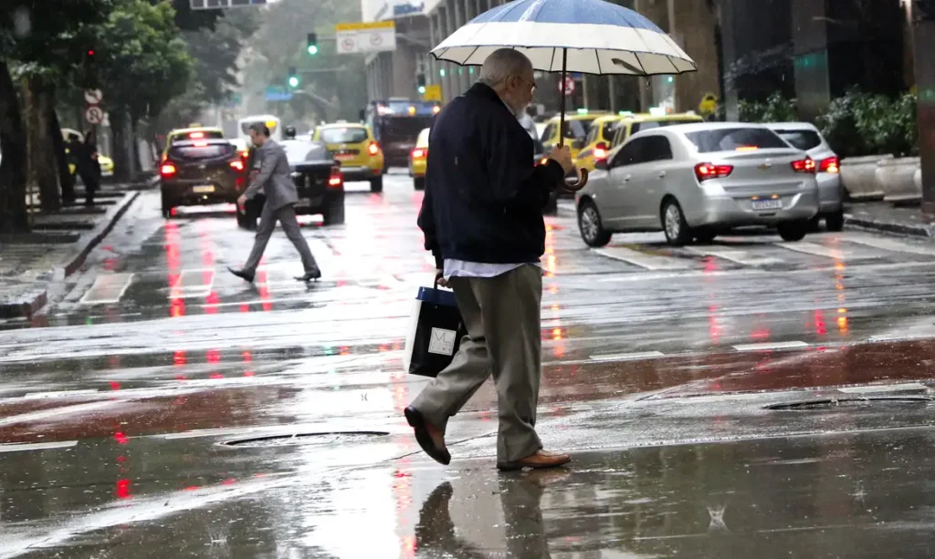 homem andando nas ruas em São Paulo com sombrinha, embaixo de chuva