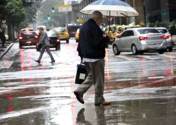 homem com sombrinha andando debaixo de chuva em sp