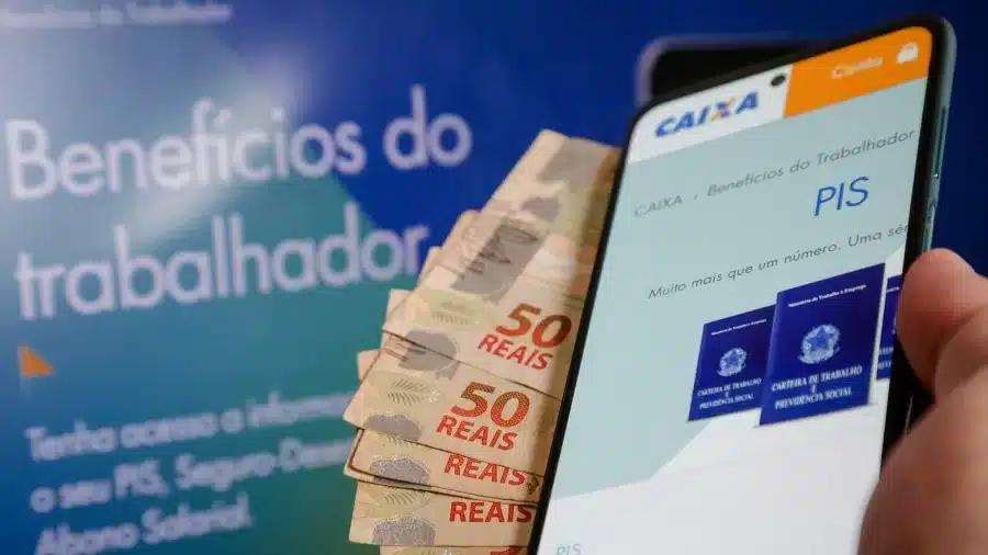 celular aberto no aplicativo da caixa para sacar o pis pasep, ao lado de notas de 50 reais