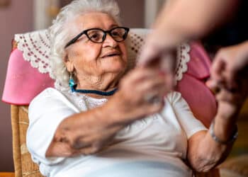 Senhora de cabelos brancos sentada e feliz com os novos benefícios para os idosos. (Fonte: Avec).