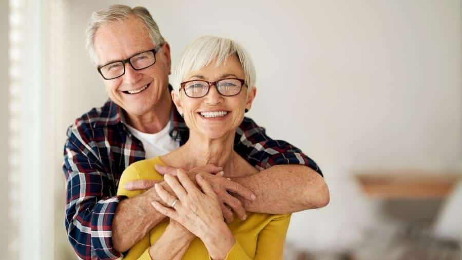 Casal abraçado e feliz com os benefícios para idosos. (Fonte: iStock).