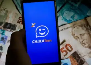 celular aberto no app caixa tem, ao lado de uma nota de 50 reais