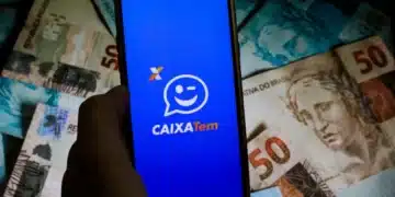celular aberto no app caixa tem, ao lado de uma nota de 50 reais