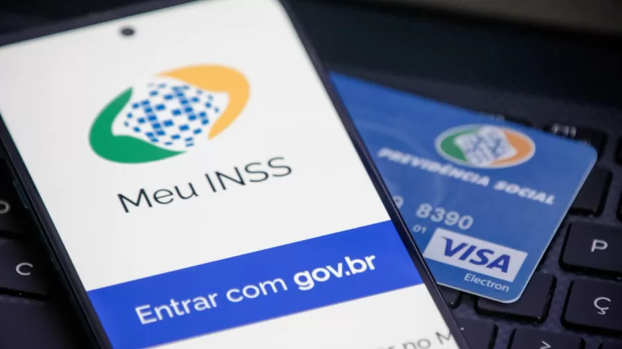celular aberto no site do inss ao lado do cartão do benefício