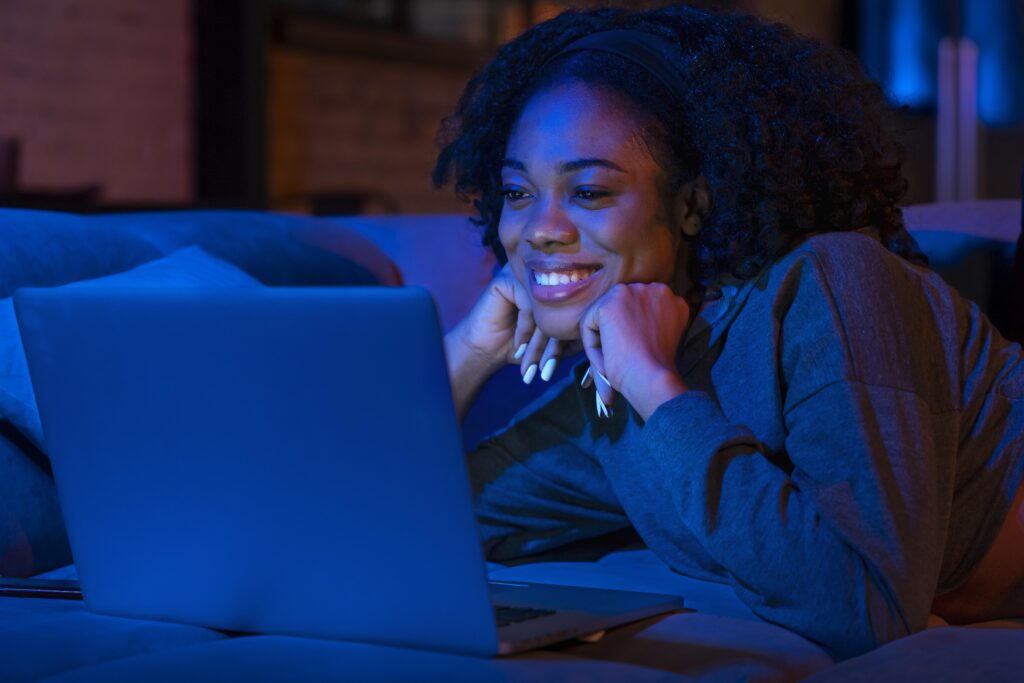 Menina feliz em frente ao computador lendo a notícia de internet de graça do nubank. (Fonte: Nubank).