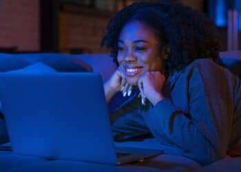 Menina feliz em frente ao computador lendo a notícia de internet de graça do nubank. (Fonte: Nubank).