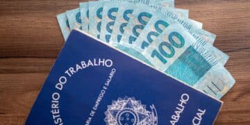 carteira de trabalho ao lado de notas de 100 reais