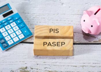 em cima de uma mesa tem cofre de porco rosa, calculadora e tablet com a frase "pis pasep"