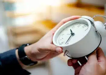 Mão ajustando relógio analógico para o horário de verão. (Fonte: Zephyr_p/Shutterstock).